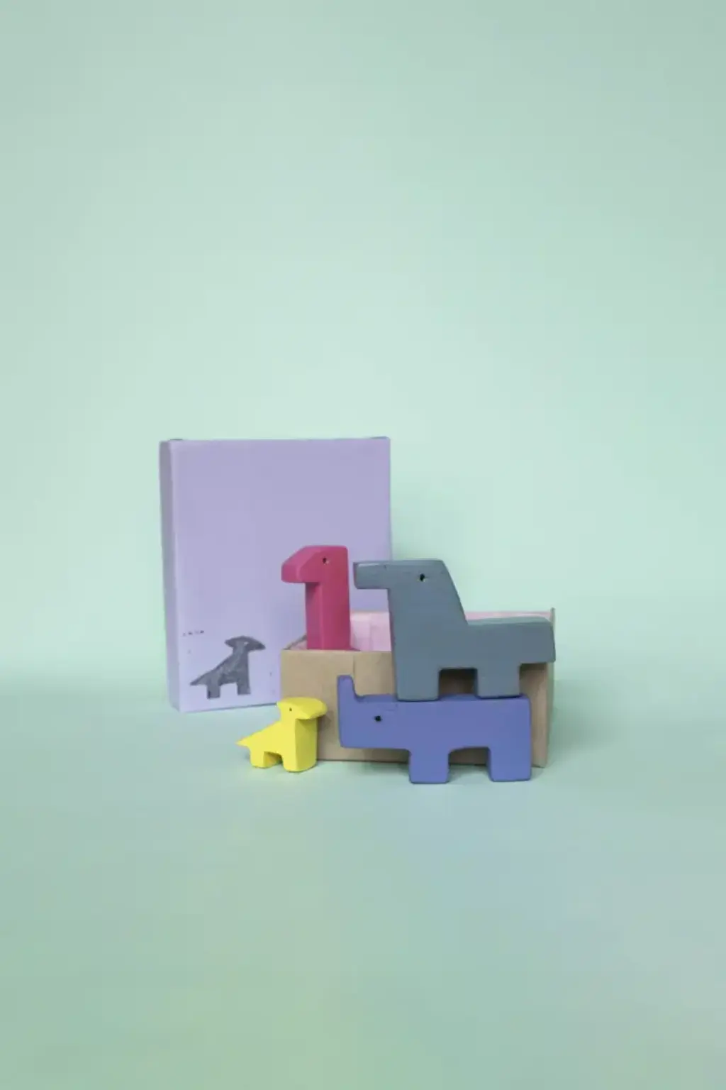 dino2 Vier Dinos stehen aufeinandergestapelt vor einer Box.