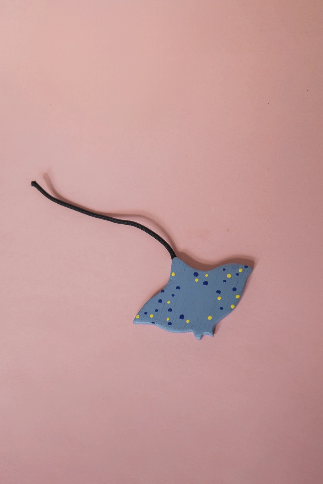 Ein Rochen aus Holz mit Punkten und Stoffschwanz.